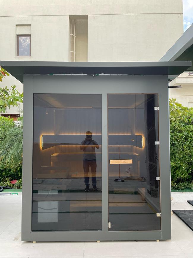 Outdoor sauna cabin installation with charcoal frame, patio setting