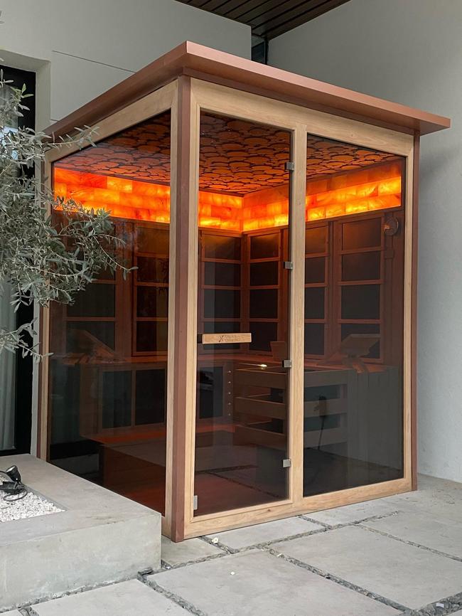 Outdoor cube-shaped sauna with glowing salt wall interior, garden installation