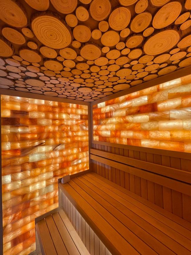 Custom circular log-slice ceiling above Himalayan salt wall in outdoor cube sauna