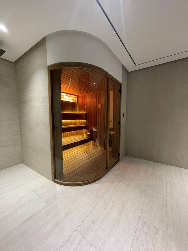 SaunaXperts Home 10 Wide view of a built-in curved sauna nook with arched glass door, custom home design