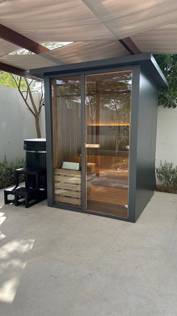 SaunaXperts Home 4 Modern charcoal-framed outdoor sauna cabin installed under a pergola in a UAE garden