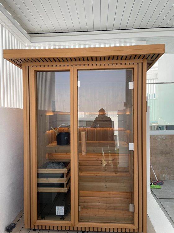 Outdoor traditional sauna cabin installed on a rooftop terrace, natural wood construction